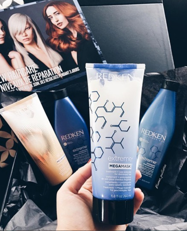 Sininen Redken Extreme Mega Mask -tuubi kädessä.